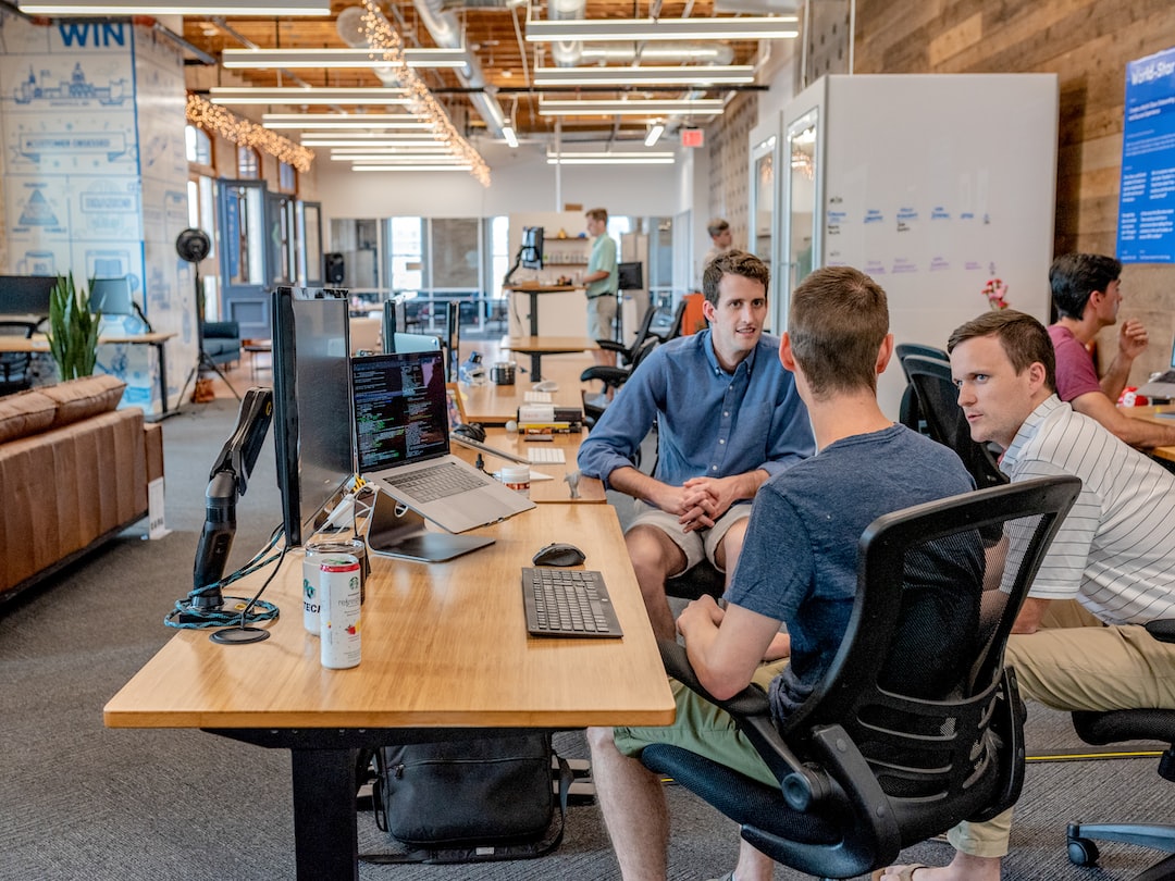 Office workers gathered around a computer screen discussing web design